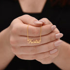 Woman holding custom name necklace designed to celebrate meaningful connections, the name on this one is KATIE.